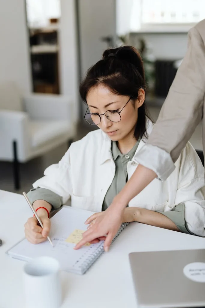 A businesswoman taking notes during a collaborative office meeting, focusing on strategy and teamwork.
