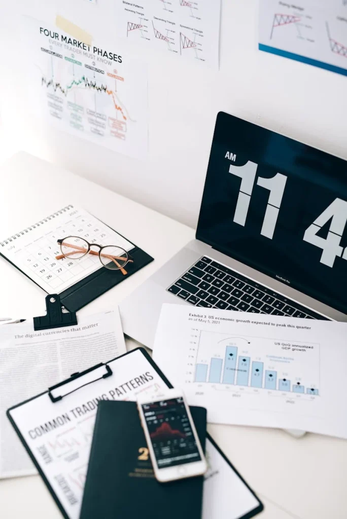 A neat desk setup with a laptop, phone, and financial documents, highlighting digital currency trends.