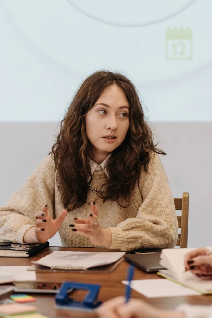A woman attentively partakes in a professional office meeting with colleagues around a table.
