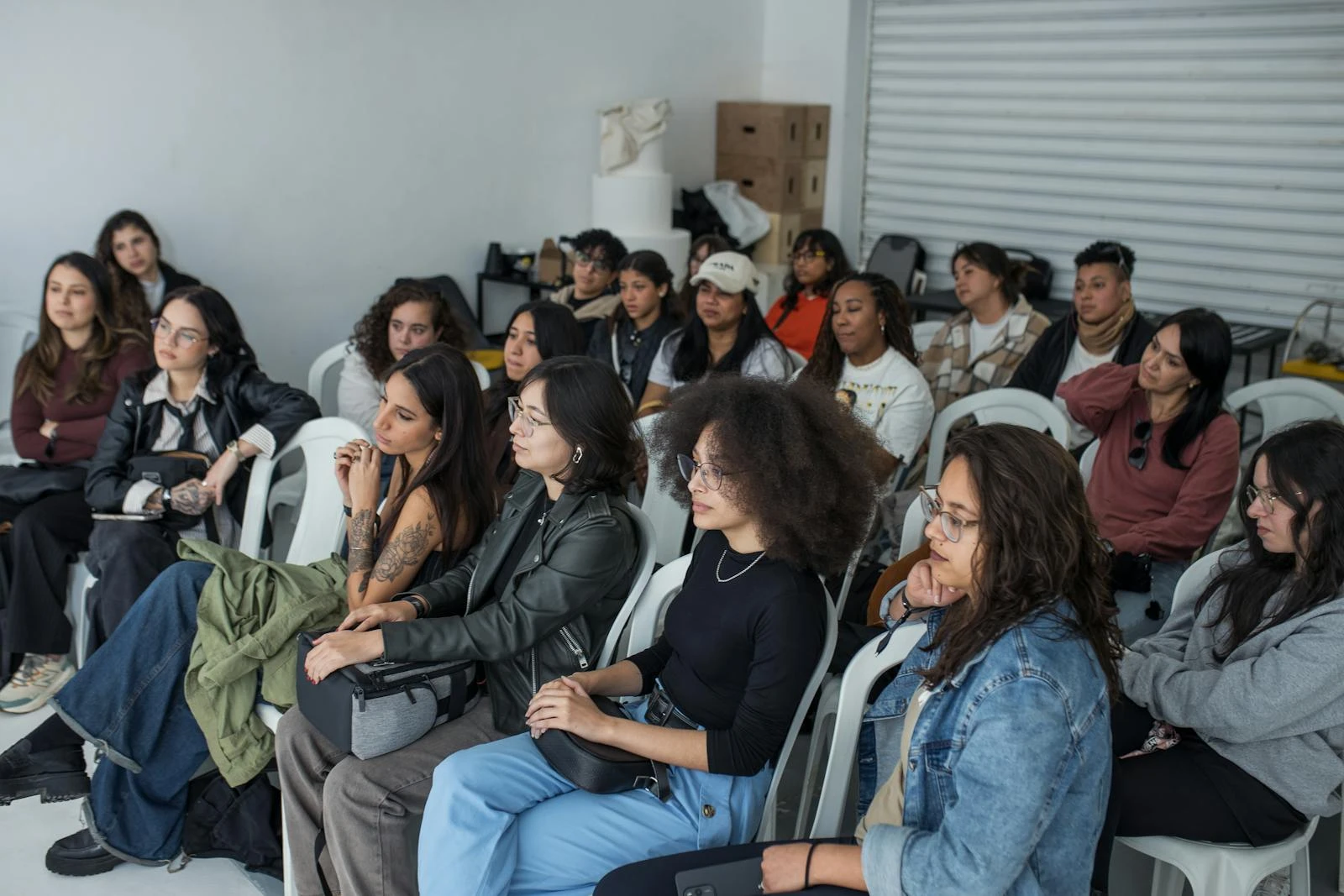 A diverse group of adults attentively listening during an indoor workshop session.