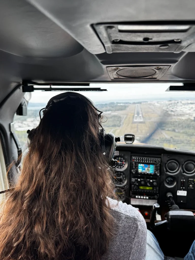 Rear view of a female pilot confidently approaching a runway in Seattle's scenic backdrop.
