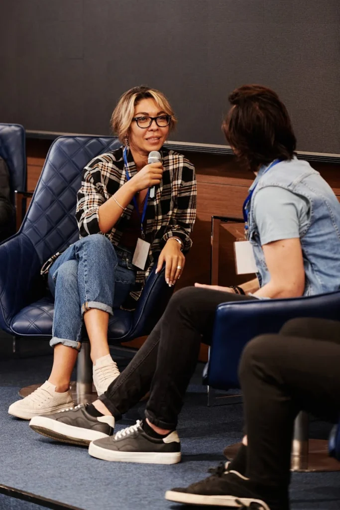 Diverse adults engaging in a casual seminar discussion indoors, featuring denim and plaids.