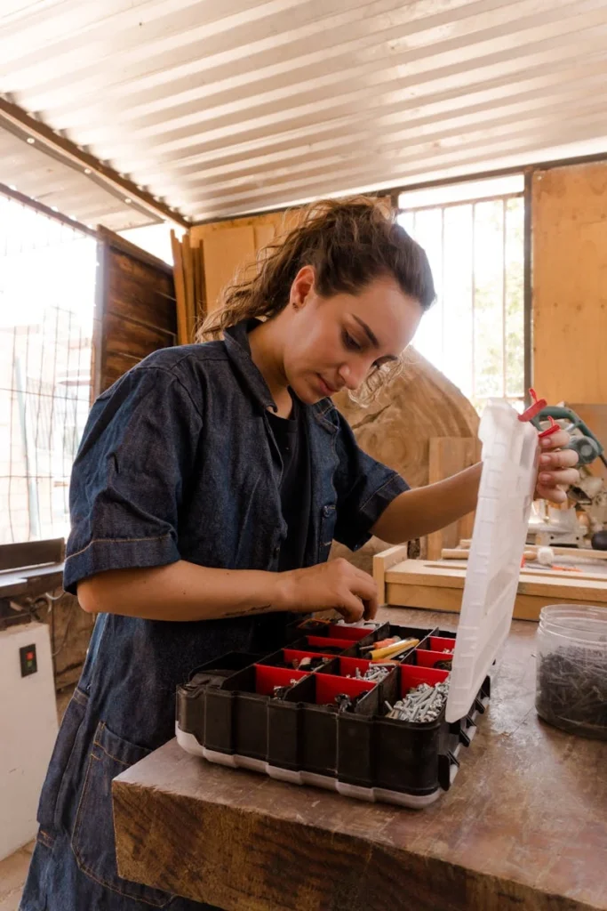 Caucasian woman organizing a toolbox in a well-lit workshop setting.