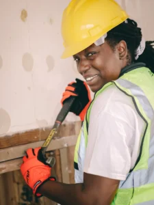 Black woman smiling while working with construction safety gear.