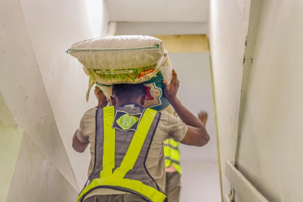 Man carrying a heavy sack up the stairs in a work environment, highlighting labor and effort.