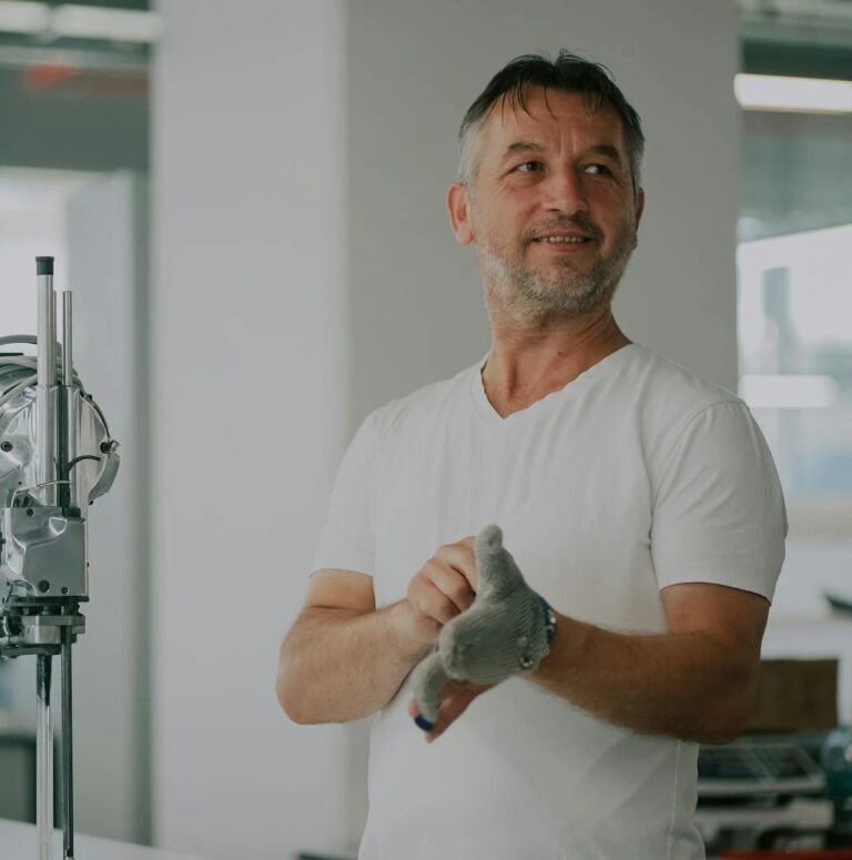 Adult man in an industrial workshop with textile machinery, preparing for work.
