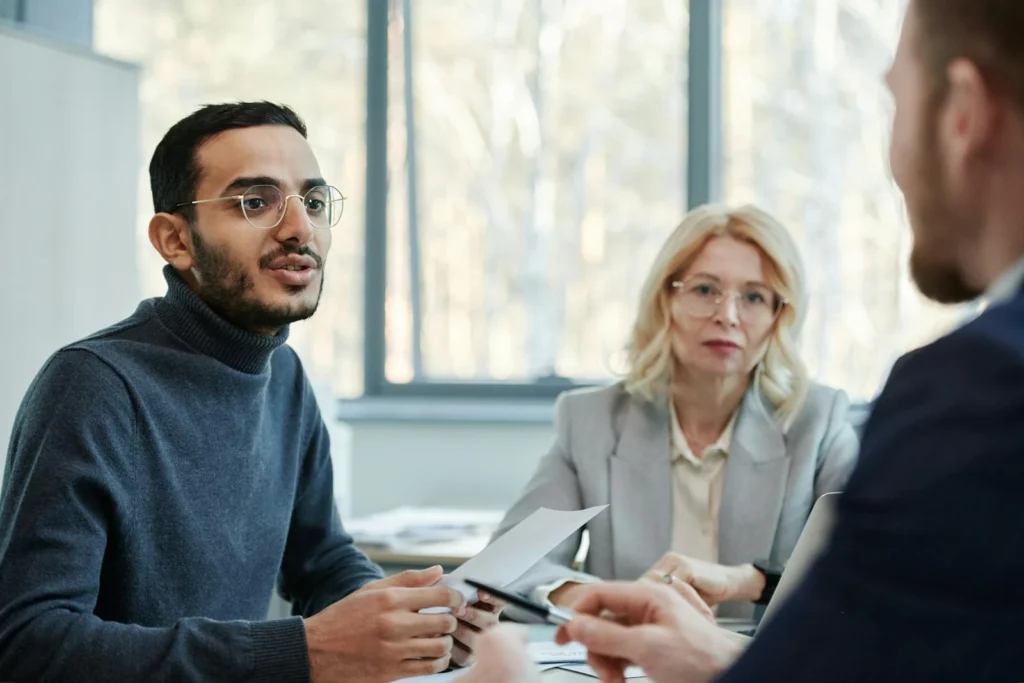 Three diverse colleagues engaging in a business discussion in a modern office setting.
