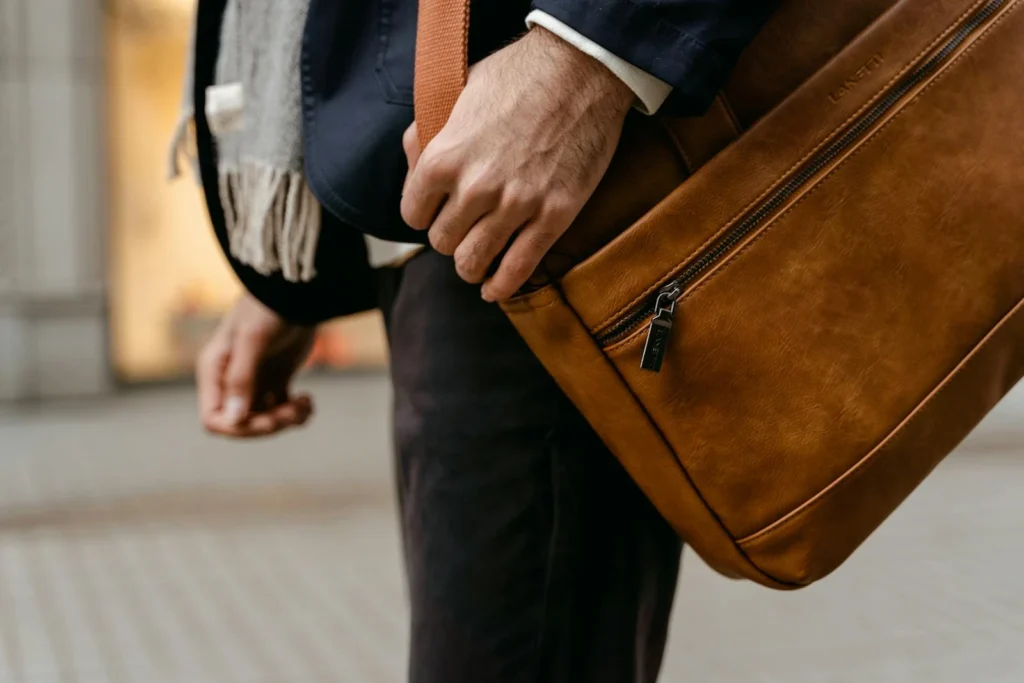 A fashionable man carrying a brown leather bag hints at modern business travel.