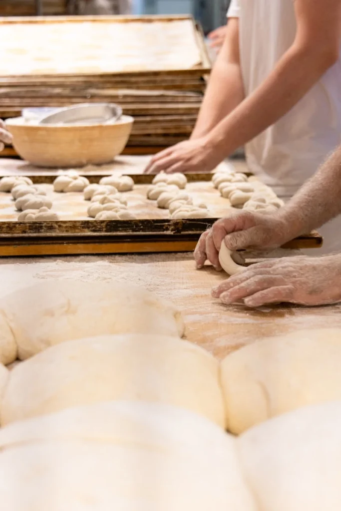 A group of people kneading dough on top of a wooden table